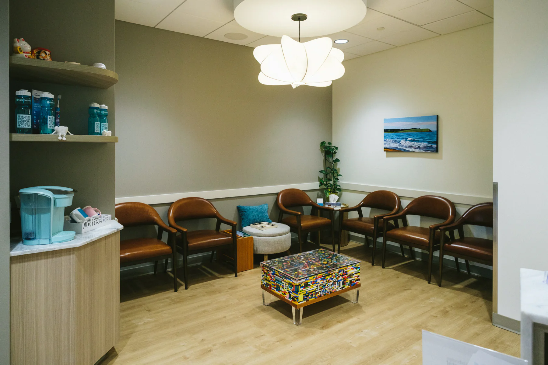 Waiting room with leather chairs, coffee station, and colourful brick coffee table