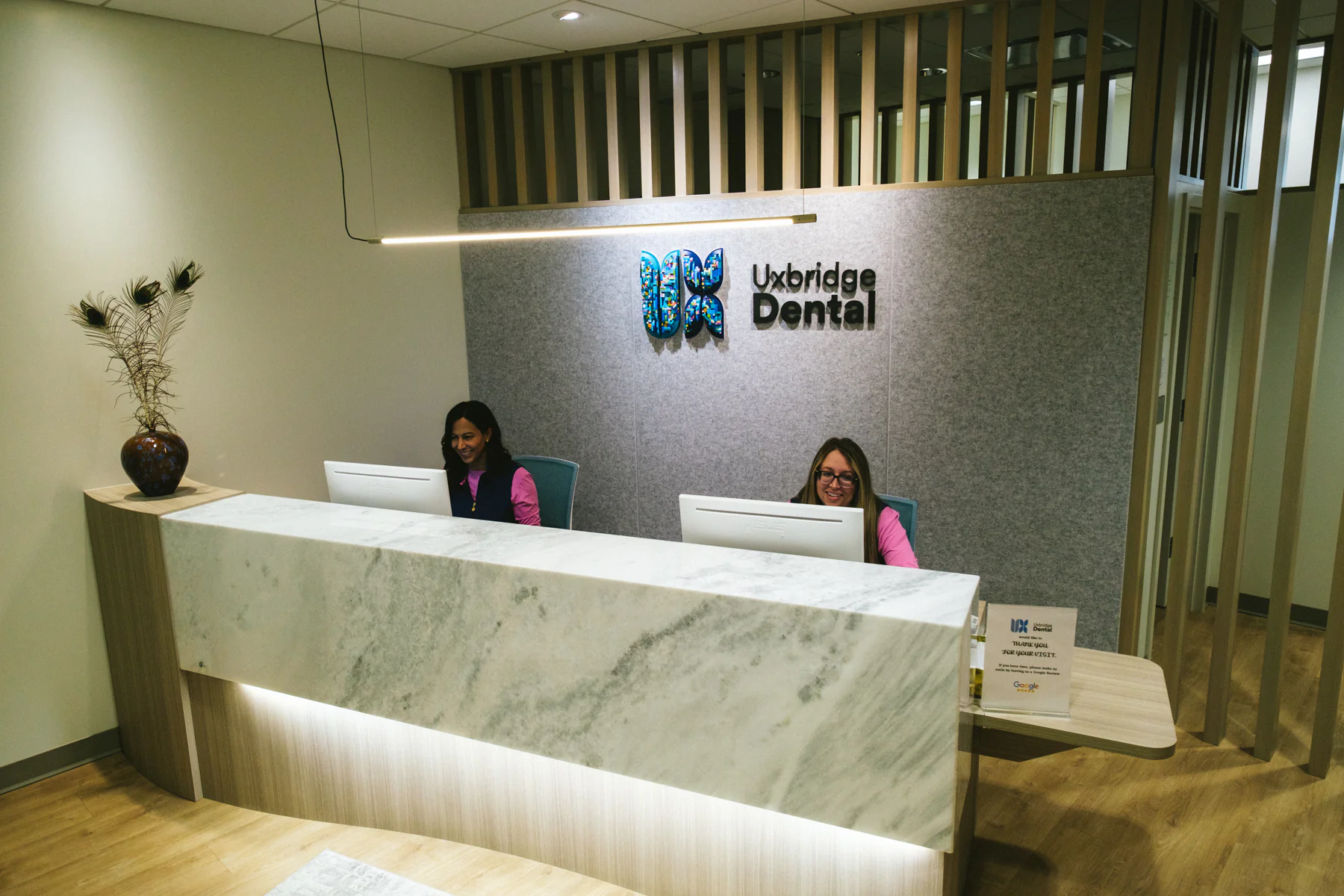 Reception desk at Uxbridge Dental Care with staff and clinic logo