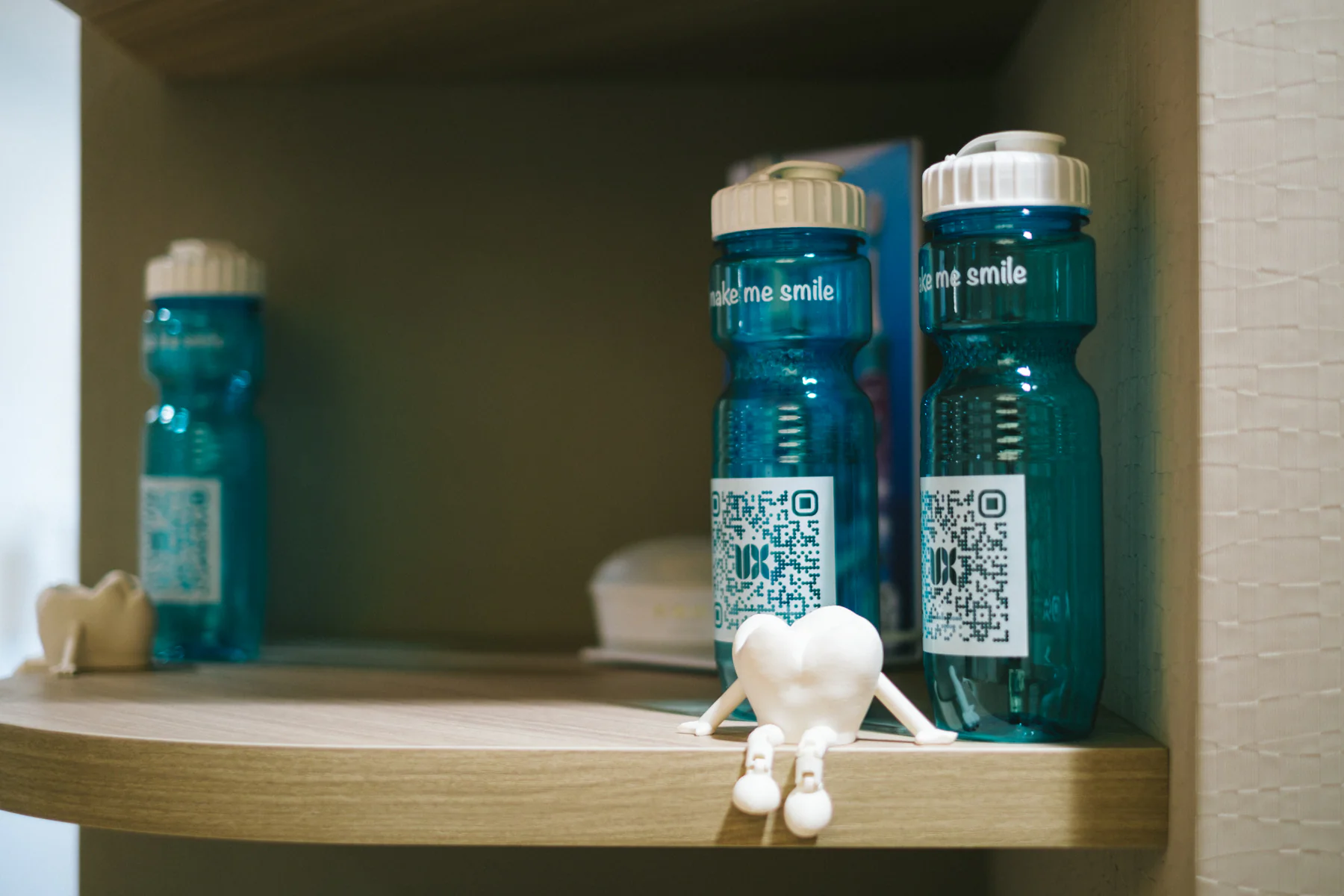 Clinic-branded water bottles and small décor on a waiting-room shelf